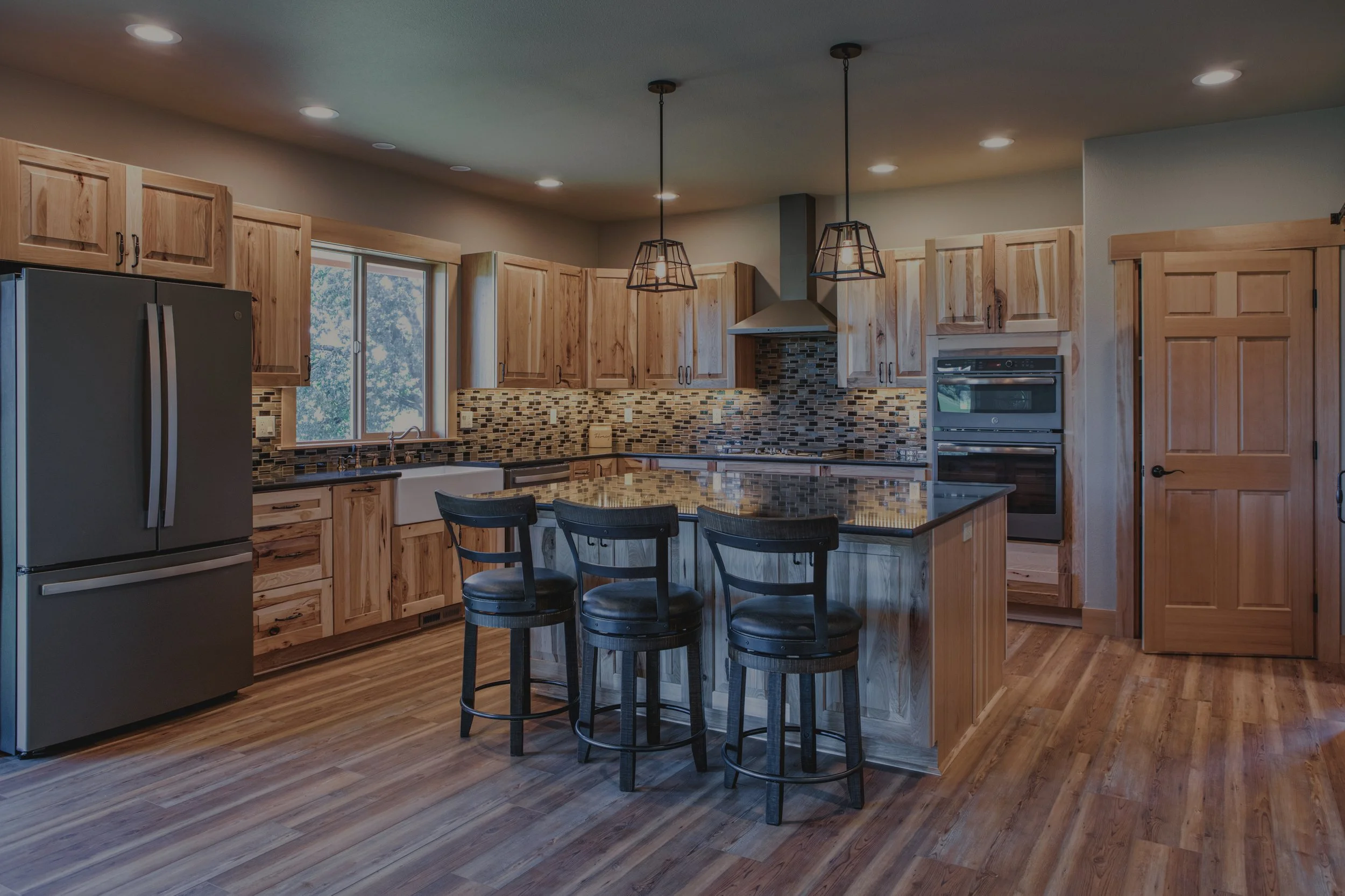 Gary's mountain-style custom home in Elma featuring rustic kitchen with wood cabinetry and granite countertops - FoxHead Construction Grays Harbor County