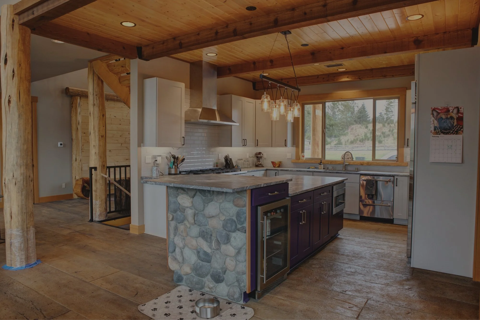 Mardy's timber frame mountain lodge custom home in Roy featuring exposed log posts and river rock kitchen island - FoxHead Construction Pierce County