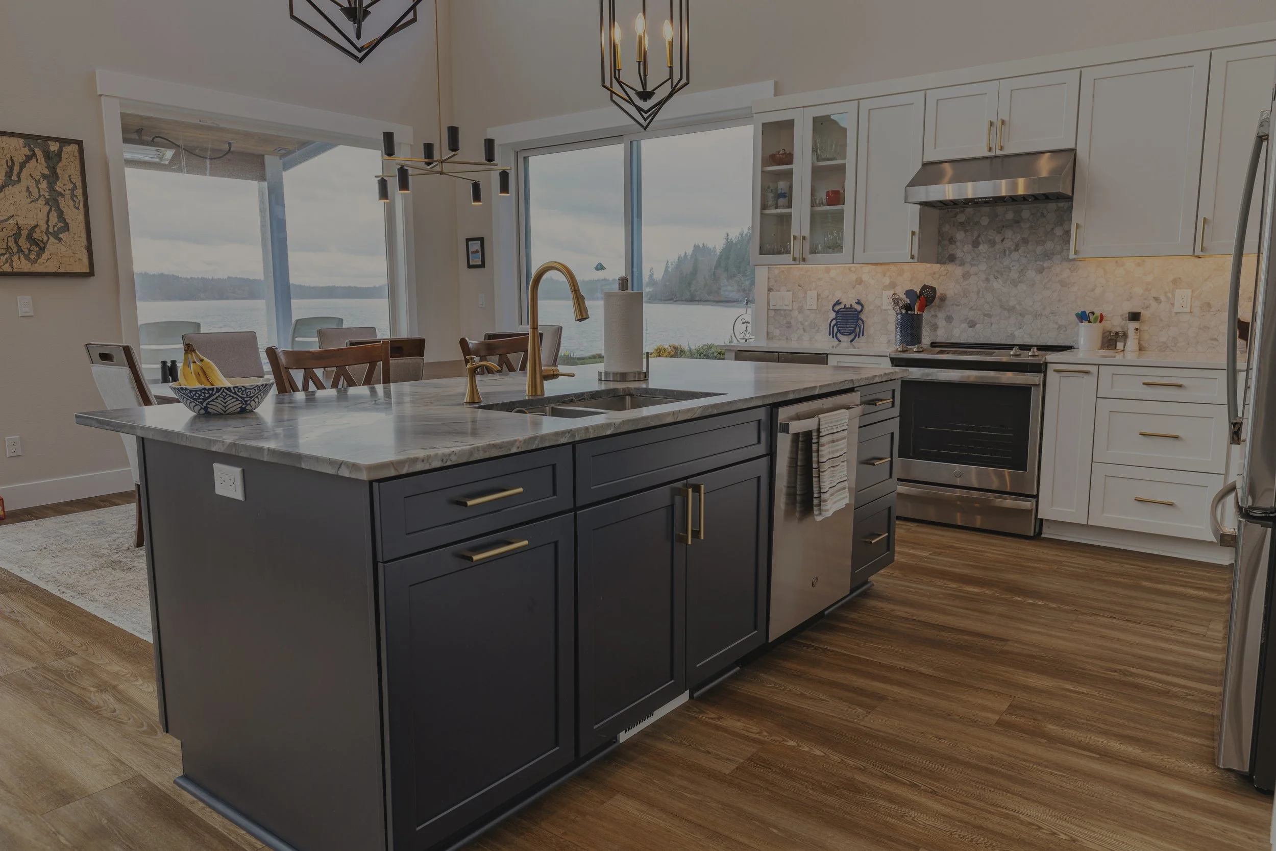 Bayview custom contemporary home on Pickering Passage featuring navy blue kitchen island with white cabinets and gold fixtures - FoxHead Construction Mason County