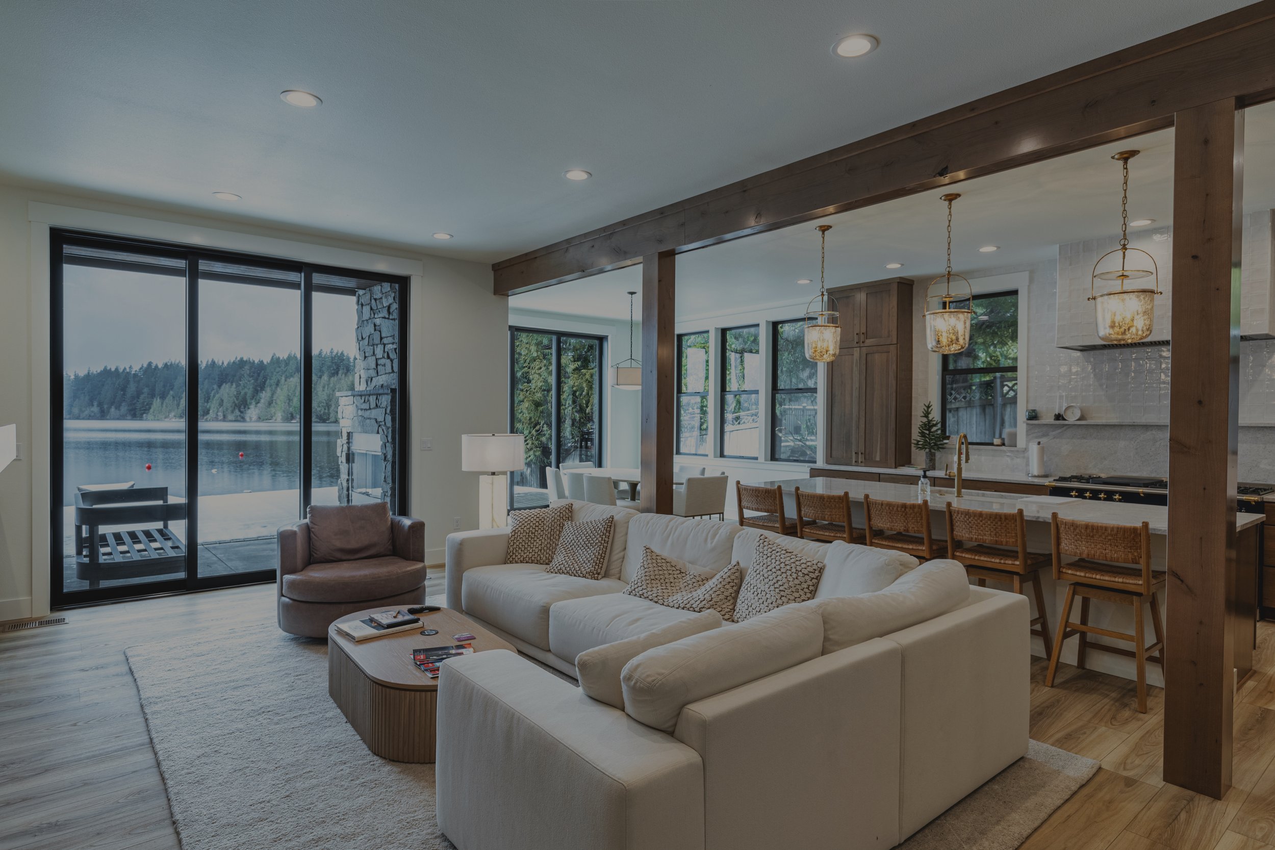 Janhunen custom lakehouse on Nahwatzel Lake featuring floor-to-ceiling windows with lake views and exposed timber trusses - FoxHead Construction Mason County