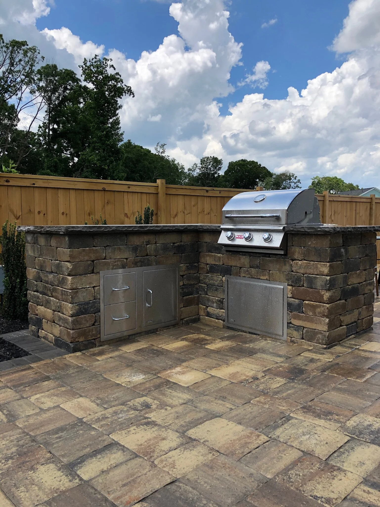 Outdoor kitchen in Greenville, Simpsonville &amp; Five Forks, SC featuring a built-in grill and stone base with stainless steel cabinets
