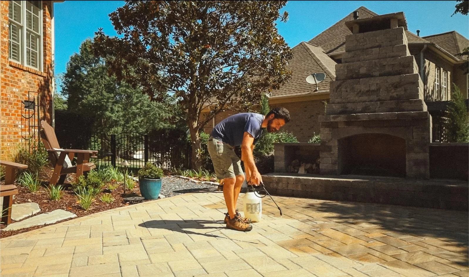 Paramount employee spraying sealant on paver patio
