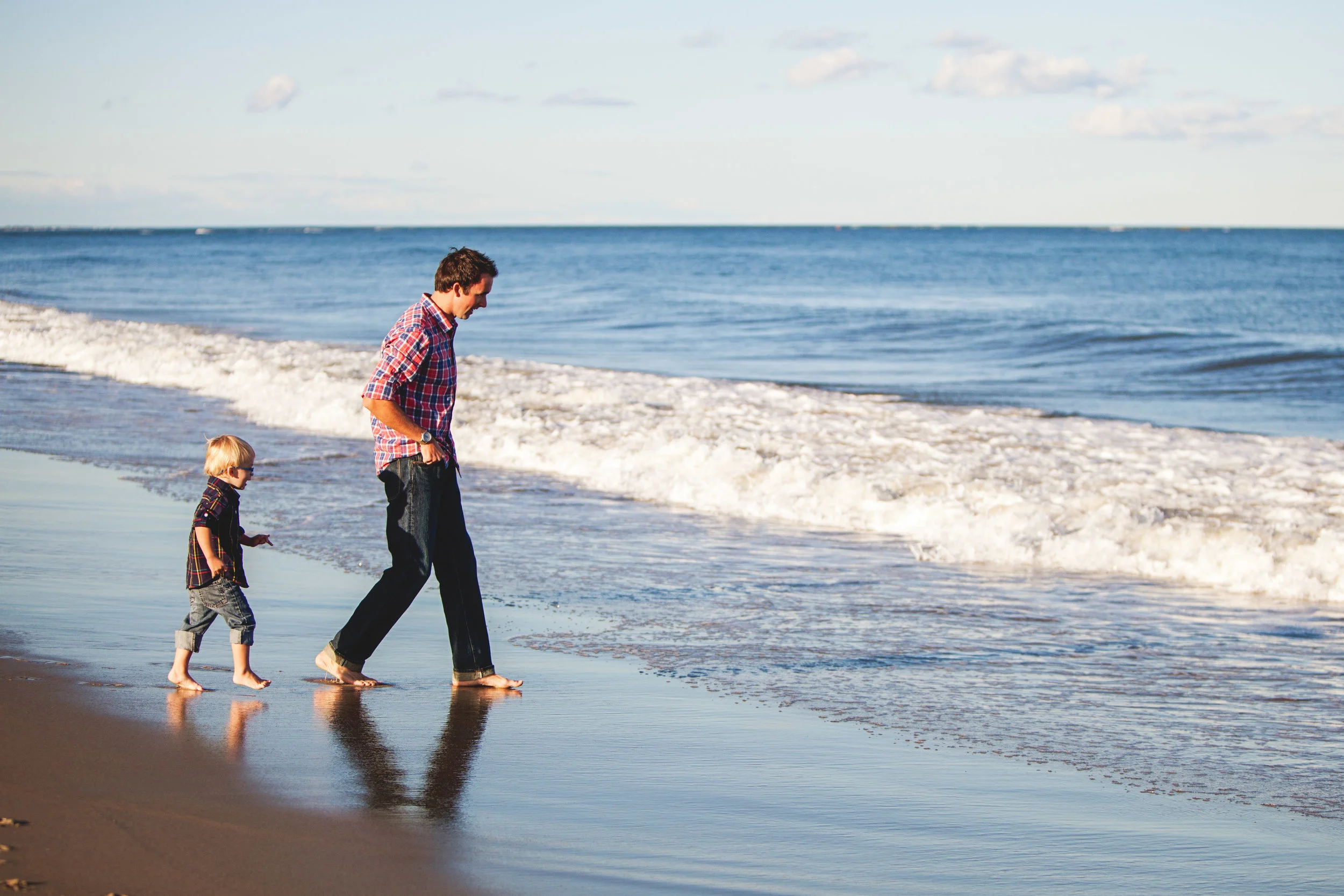 Father and young son walking along the beach