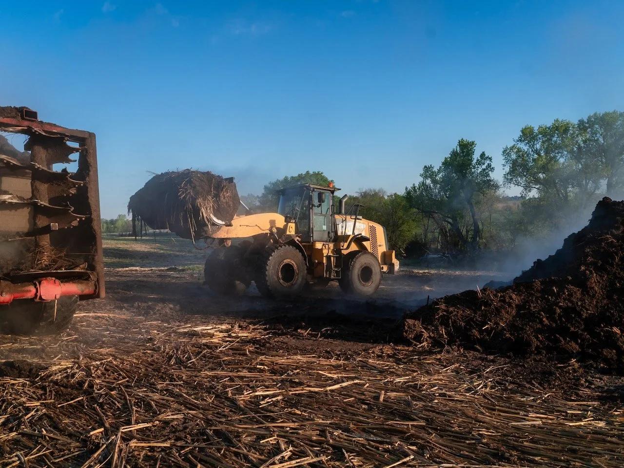 Tractor picking up fresh compost on a Nebraska farm field