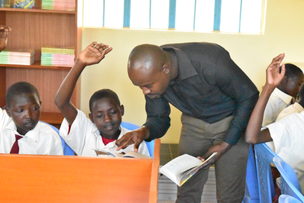 English teacher Mr. Okello helps one of his 7th grade students in the library.