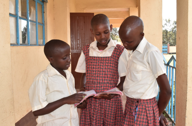 Students at the Kakenya Center look at a book outside