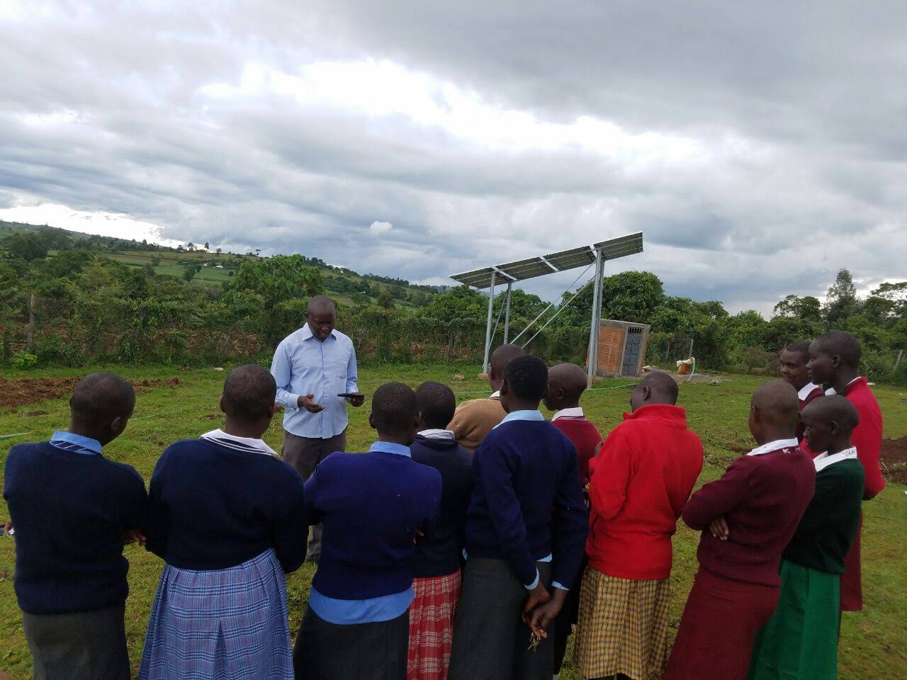 Headteacher Daniel Kishoyian greets the girls outside on their first day. Some of the school’s solar panels can be seen in the back right.
