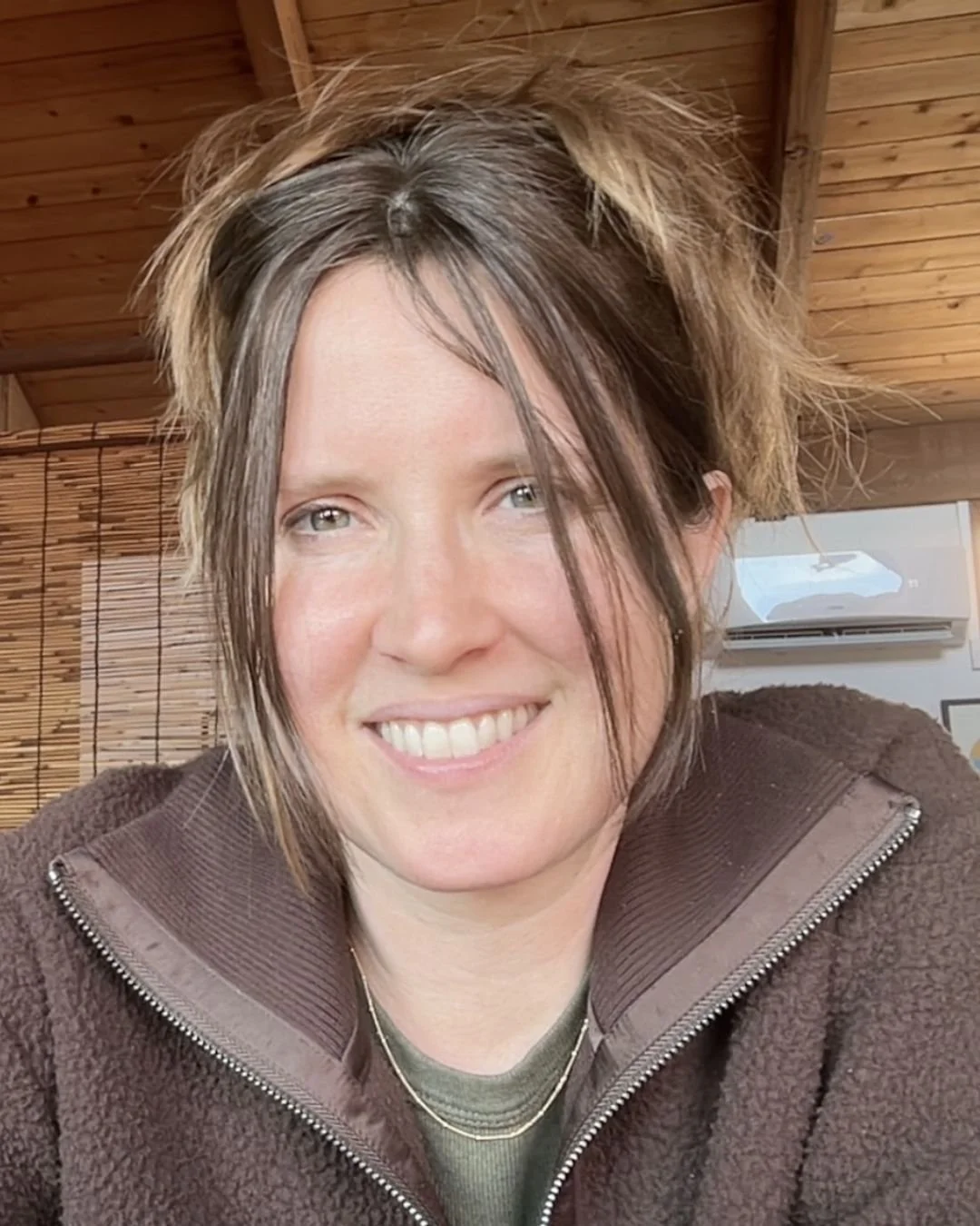 picture of anne shelton crute acupuncturist at ritual health acupuncture in berkeley. she is smiling and looking at the camera, with wood elements behind her in her berkeley clinic