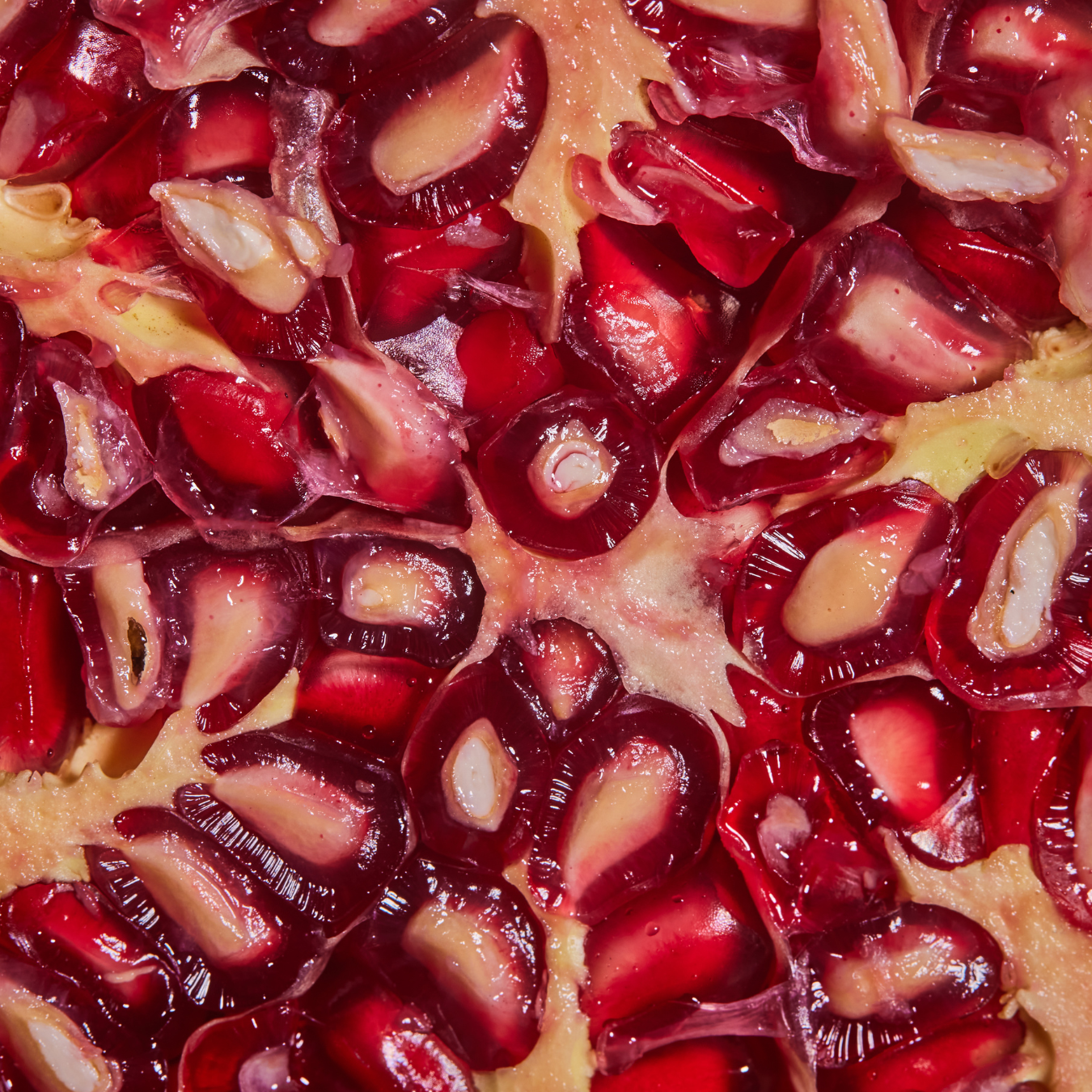 Close-up of pomegranate seeds with red and white interior.