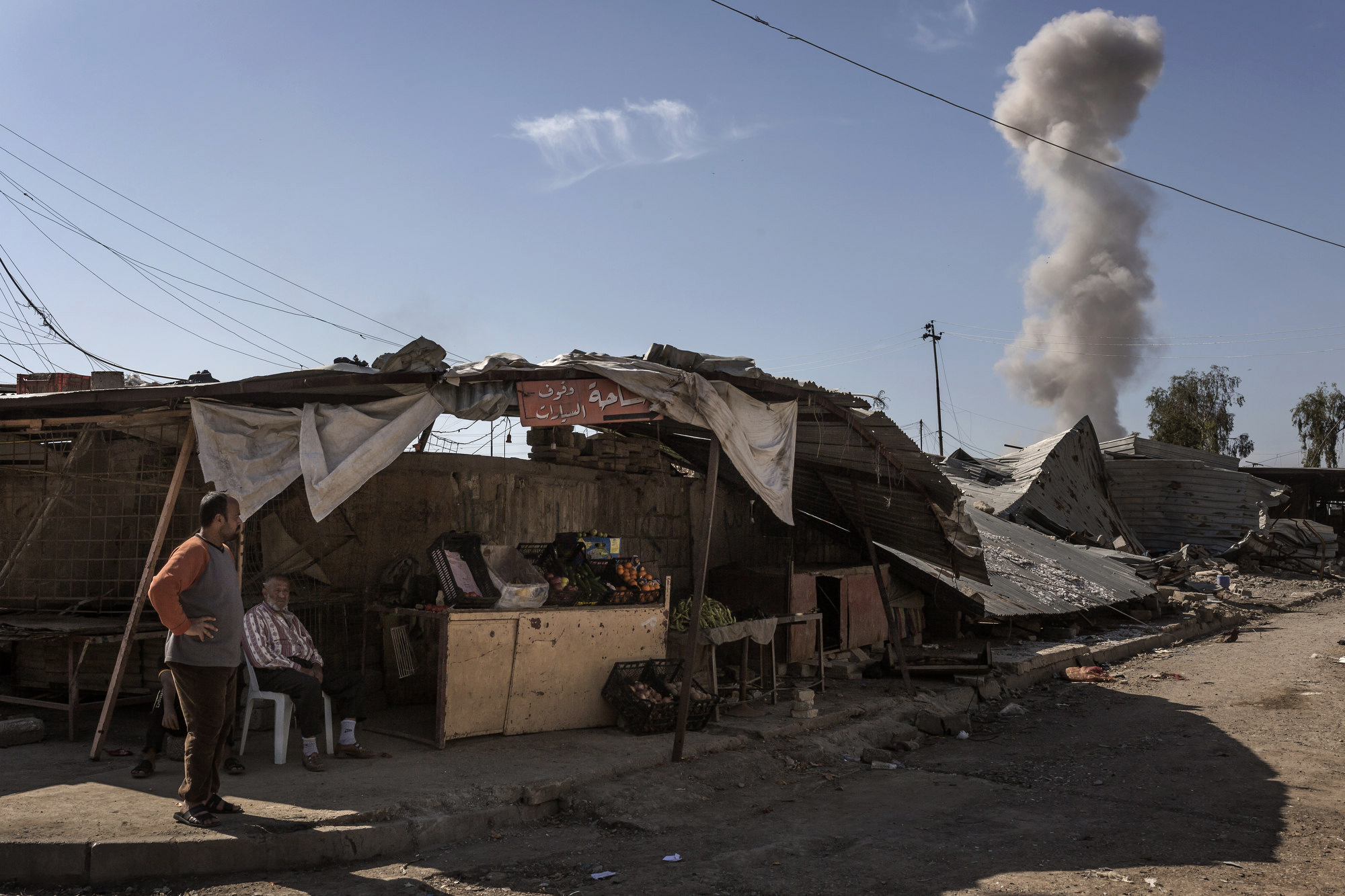  Residents of a recently liberated Mosul neighbourhood look on as an Islamic State car bomb detonates in the near distance. 