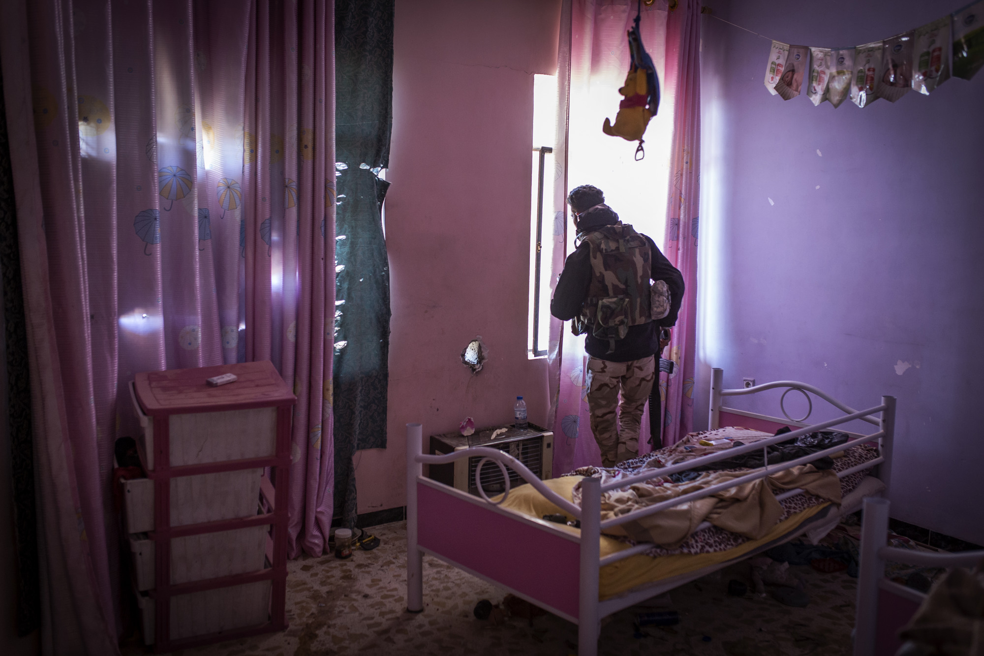 An Iraqi soldier peers through the window of a child's bedroom during clashes with Islamic State forces in Mosul. 