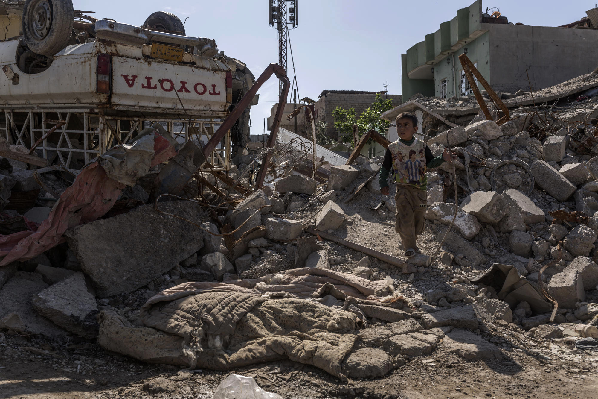  A child crosses rubble in Mosul near the covered corpse of an Islamic State militant. 