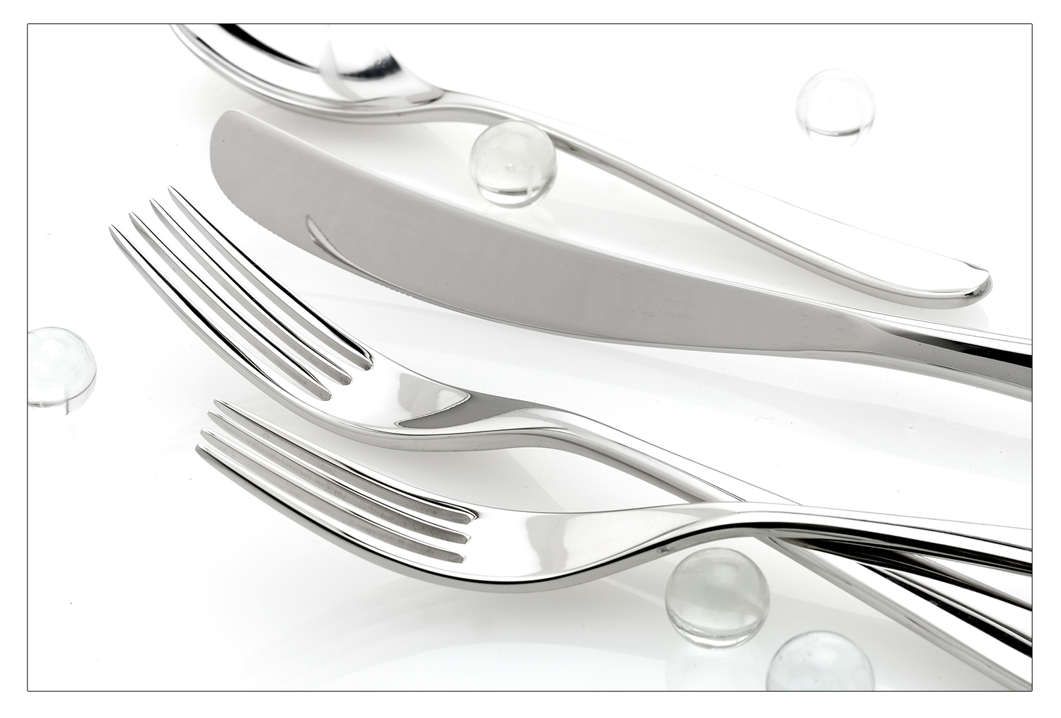 Flatware on white with clear glass marbles. Product Photo.