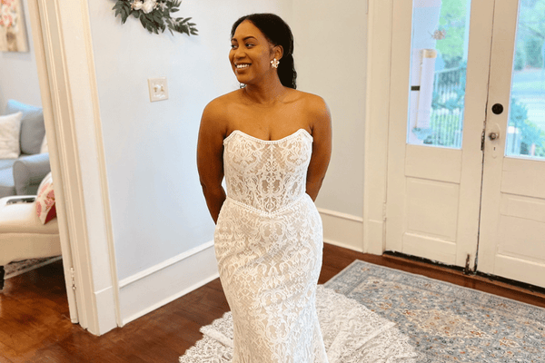 Bride wearing a strapless lace fitted wedding dress during a bridal boutique fitting.