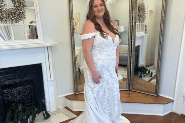 Bride in front of the mirror trying on her off the shoulders white wedding gown