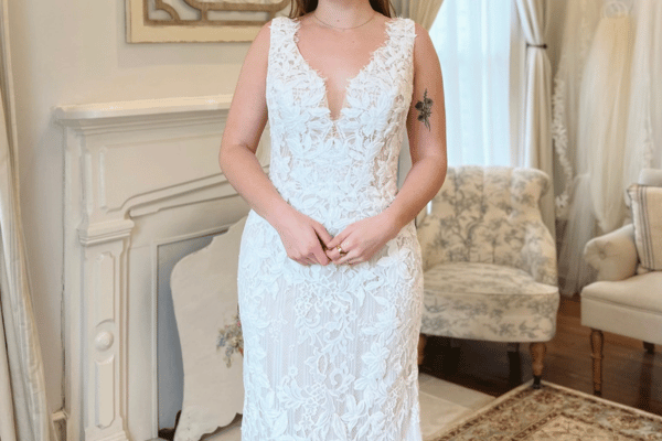 Bride wearing a lace fit-and-flare wedding dress with a deep V neckline and fitted silhouette.