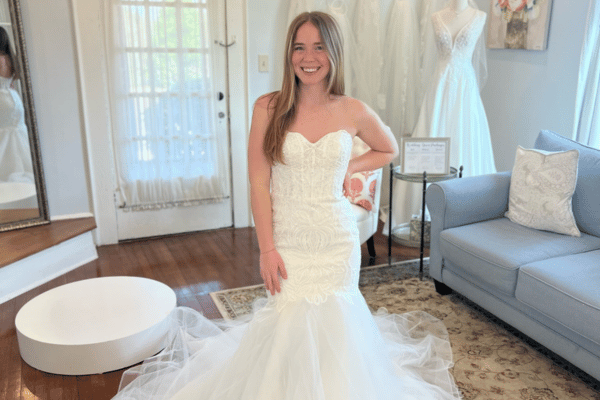 Bride trying on fitted lace mermaid wedding dress at bridal boutique