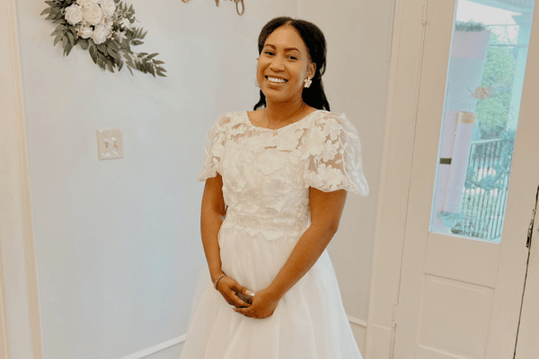 Bride wearing a modest wedding dress with floral lace, short puff sleeves, and a flowing tulle skirt.