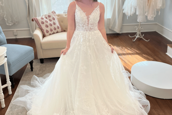 Bride wearing a lace ball gown wedding dress with a deep V neckline and layered tulle skirt.