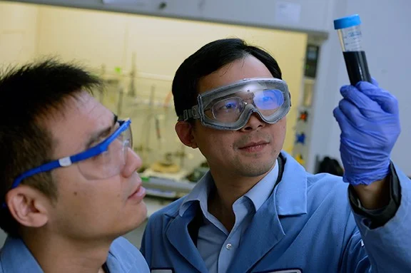 Image caption:Chao Wang (right) inspects a glass vial containing cobalt cores, each coated with a thin layer of platinum. At left is postdoctoral fellow Lei Wang.