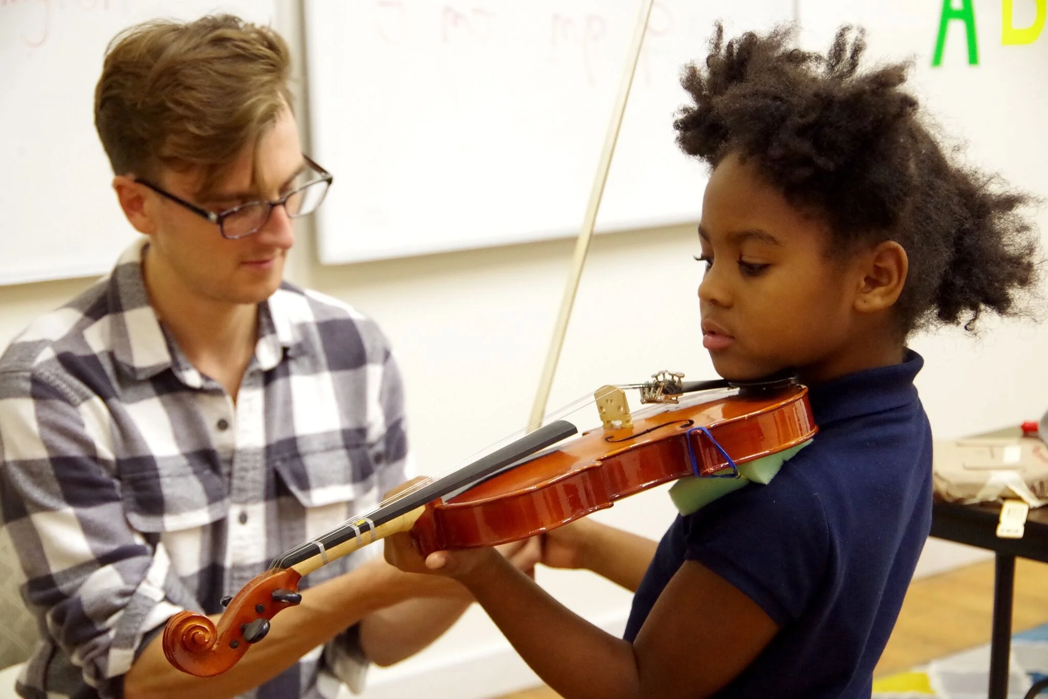 Mr. Patrick shows Laura how to hold her bow 