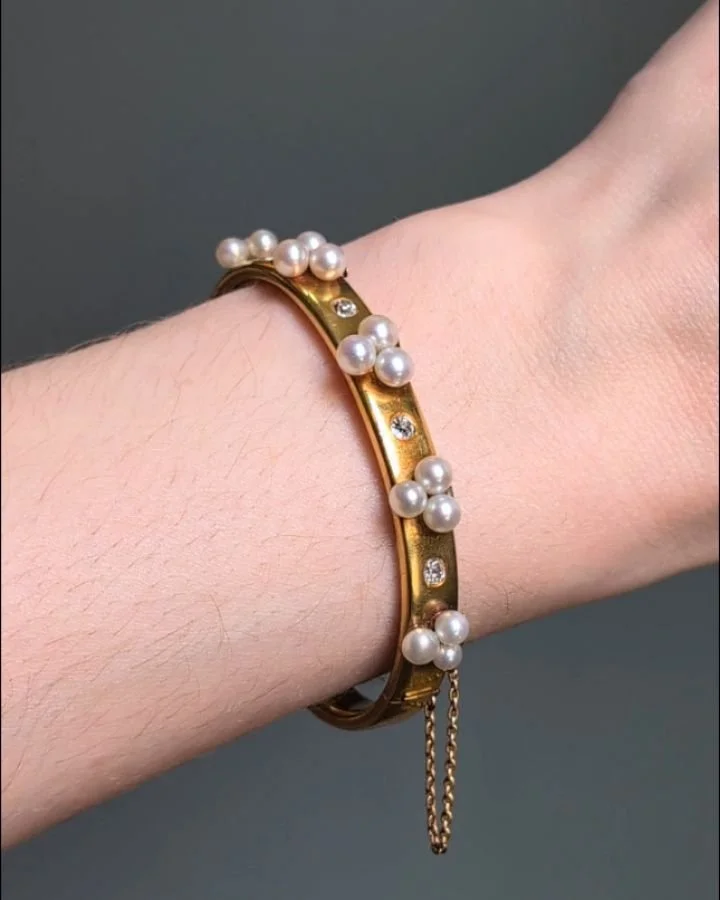 An antique diamond and natural pearl bangle, the bloomed 18kt gold band with applied pearl trefoil clusters with single bezel set diamond intersections. French circa 1876. Available @simonteaklejewelry #antiquepearlbangle #pearlanddiamondbangle #natu