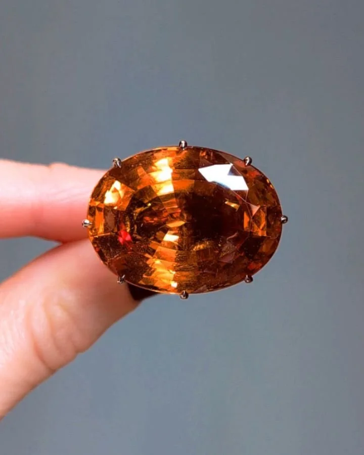 An oval cut Imperial topaz single-stone ring by Taffin, in a circular-cut diamond latticework basket with a pave-set spinel collar, mounted in 18kt white and rose gold hoop with ceramic interior. Available @simomteaklejewelry #taffin #jamesdegivenchy