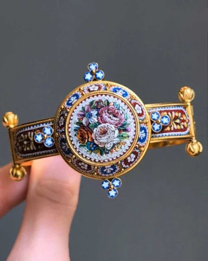 An antique revivalist micro mosaic bangle, the central large circular floral motif, with a foliate surround and panelled shoulders on a granulated band, mounted in 18kt bloomed gold, in a fitted box. English circa 1870. Available @simonteaklejewelry&