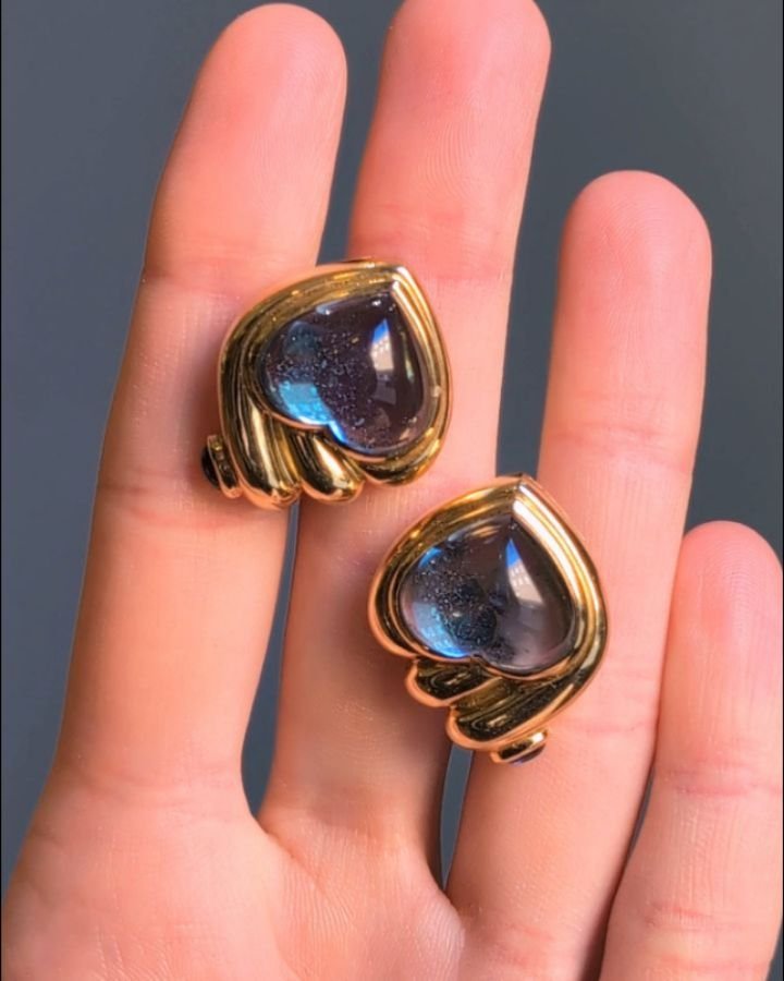 A pair of blue topaz earrings by Bulgari, each heart shaped topaz with an asymmetric scroll surround and  cabochon sapphire detail, mounted in 18kt gold. Circa 1980. Available @simonteaklejewelry  #vintagebulgariearrings #bulgariearrings #bulgarijewe