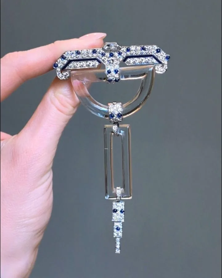 An Art Deco diamond and rock crystal brooch, the semi circular open crystal motif suspending a rectangular crystal motif with pave set diamond and cabochon sapphire platinum mounts. Circa 1925. Available @simonteaklejewelry #artdecobrooch #artdecoroc