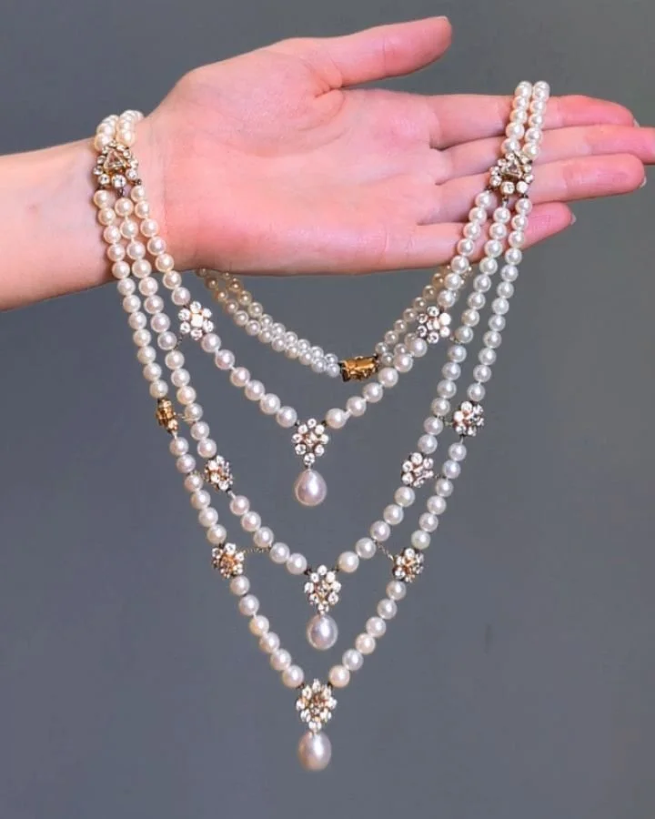 A cultured pearl and diamond necklace by Cartier, designed as a three row pearl swag interspersed with diamond cluster motifs and each swag with a single pearl drop. Cartier Paris circa 1970. Available @simonteaklejewelry #cartiernecklace #cartierpea