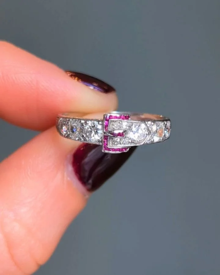 An Art Deco diamond buckle ring, with calibre cut ruby detail, mounted in platinum. Circa 1920. Available @simomteaklejewelry #artdeco #artdecojewelry #artdecoring #artdecoruby #rubyring #diamondbucklering #rubyanddiamondring #antiquebuckle #simontea