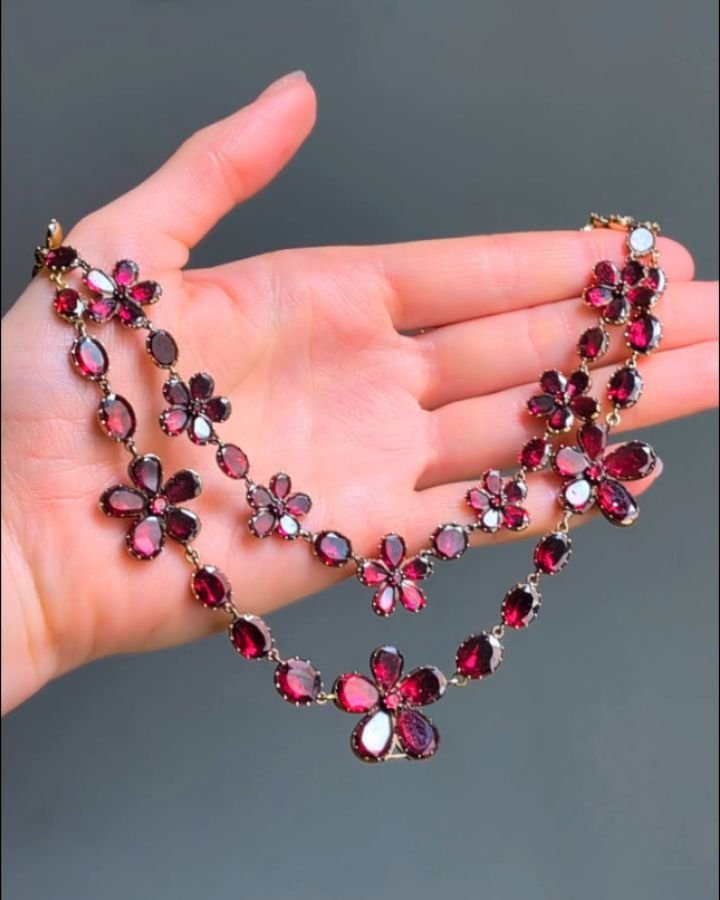 An antique garnet necklace, designed as a two row festoon of pentafoil garnet clusters with oval collet intersections. mounted in gold. English circa 1810. Available @simonteaklejewelry #antiquegarnet #antiquegarnetnecklace #antiqueflowernecklace #ge