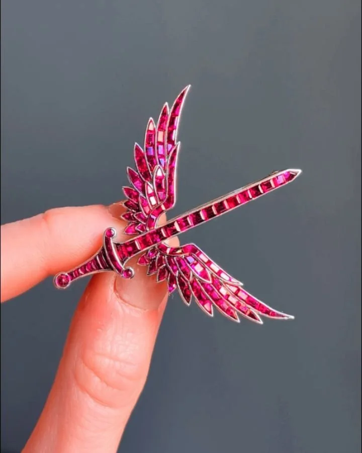 A ruby brooch by Hennell, designed as the insignia of 601 Squadron in calibre cut rubies, the central sword between two wing motifs, mounted in platinum, in a fitted box. London circa 1930.

&ldquo;No. 601 Squadron was formed at RAF Northolt on 14 Oc