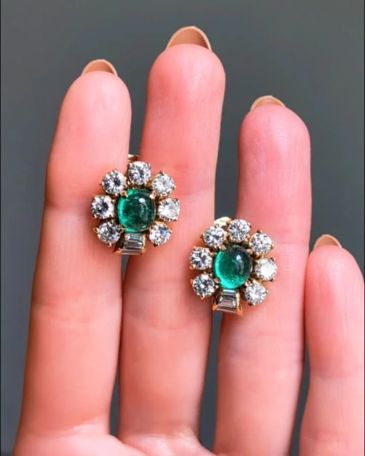 A pair of emerald and diamond earrings by Bulgari, each cabochon emerald with a spaced circular cut diamond surround with baguette cut diamond detail, mounted in 18kt gold. circa 1980. Available @simonteaklejewelry #bulgariearrings #bulgarijewelry #b
