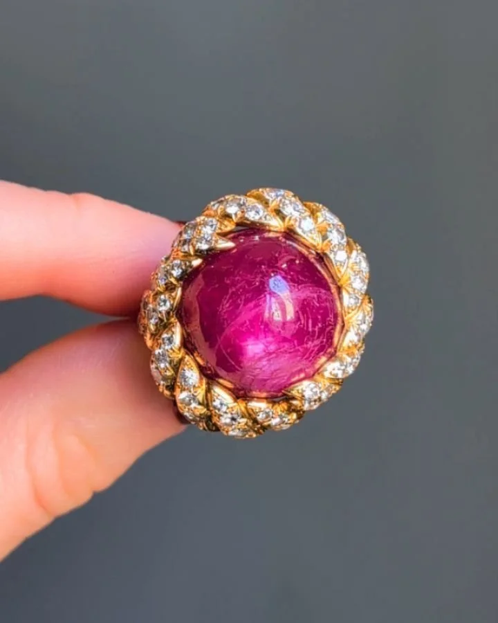 A cabochon ruby and diamond ring by Mauboussin, the circular ruby within a diamond set rope twist 18kt gold mount. The weight of the ruby is approximately 28.00 carats. Paris circa 1965. Available @simomteaklejewelry #rubyring #mauboussin #mauboussin