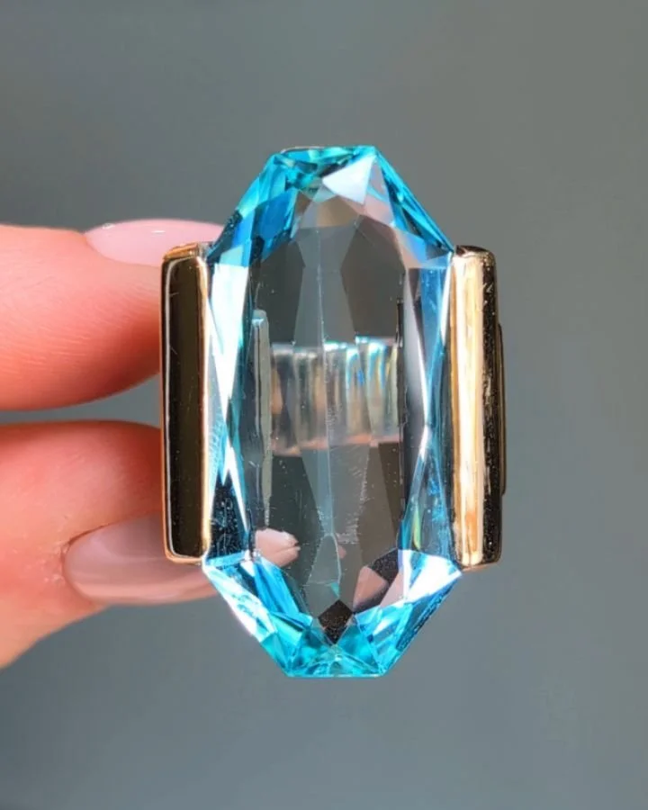 An Art Deco aquamarine single stone ring, the elongated octagonal aquamarine within a stylised geometric gold and platinum mount. The weight of the aquamarine is approximately 26.00 carats. French circa 1935. Available @simomteaklejewelry #artdeco #a