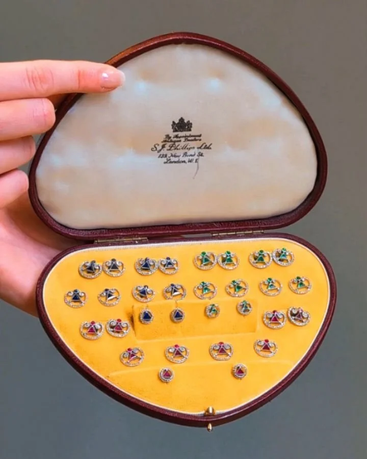 An extraordinary Edwardian dress set, three sets of open scroll design with a central triangular cut gem, the three sets in emerald, sapphire and ruby comprising cufflinks buttons and studs all mounted in platinum, in a fitted case. Edwardian circa 1