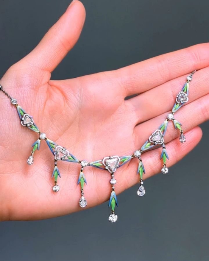 A Belle Epoque diamond necklace, designed as a series of graduated triangular cut diamonds within green and blue enamel foliate panels suspended in fringe of circular and pear shaped diamonds mounted in platinum. Circa 1900. Available at Moda Operand