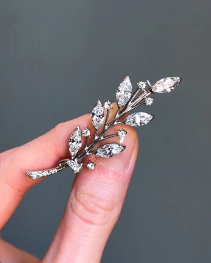 A diamond foliate spray brooch by Tiffany, designed with six marquise diamonds and circular cut diamond detail, mounted in platinum. Circa 1970. Available @simonteaklejewelry #tiffanybrooch #vintagetiffanyjewelry #vintagetiffany #vintagediamond #diam
