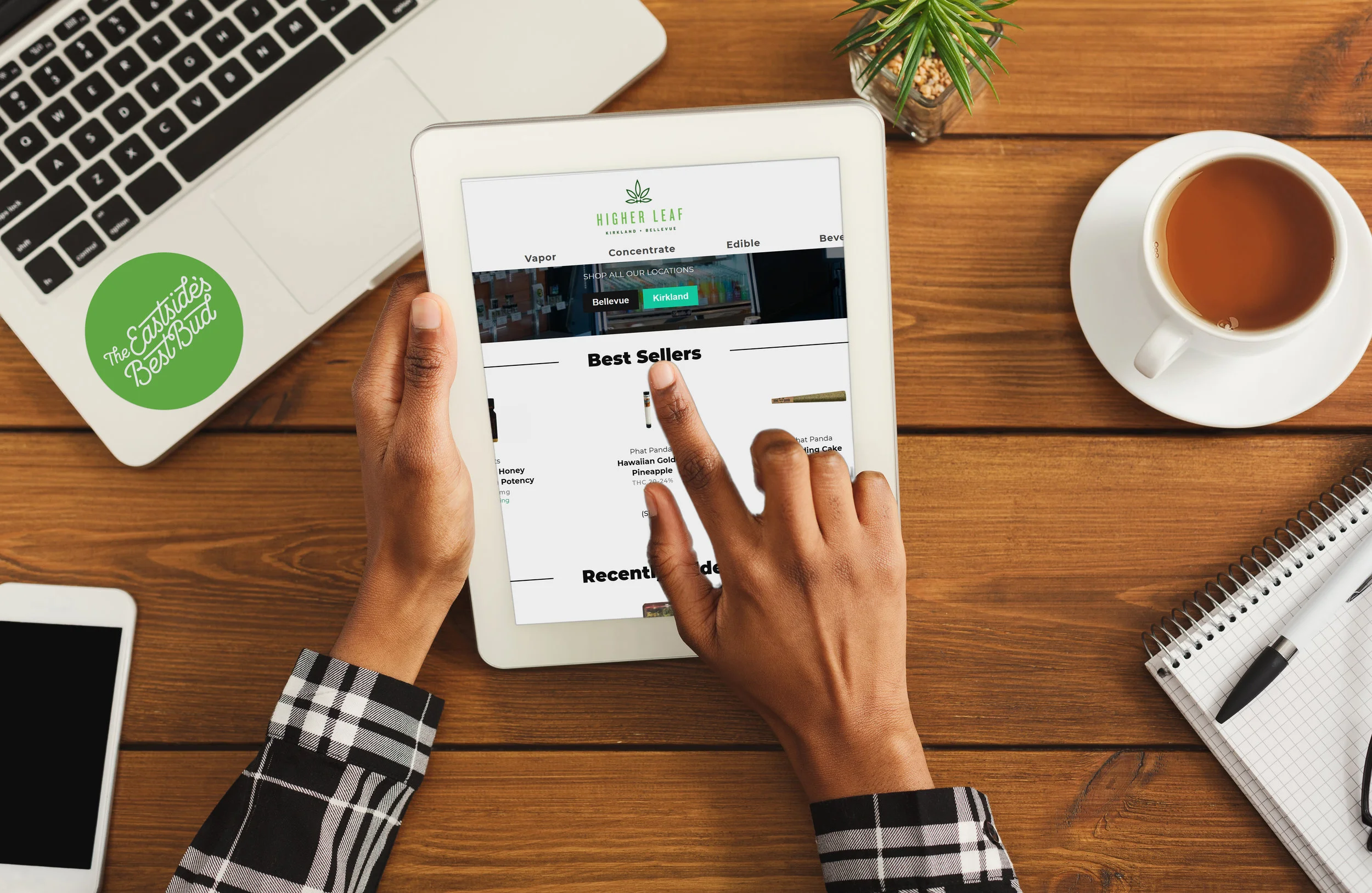 Black woman pointing with finger on digital tablet with blank screen for advertisement. Top view of african-american hands, laptop keyboard, coffee, smartphone on wooden office table background.