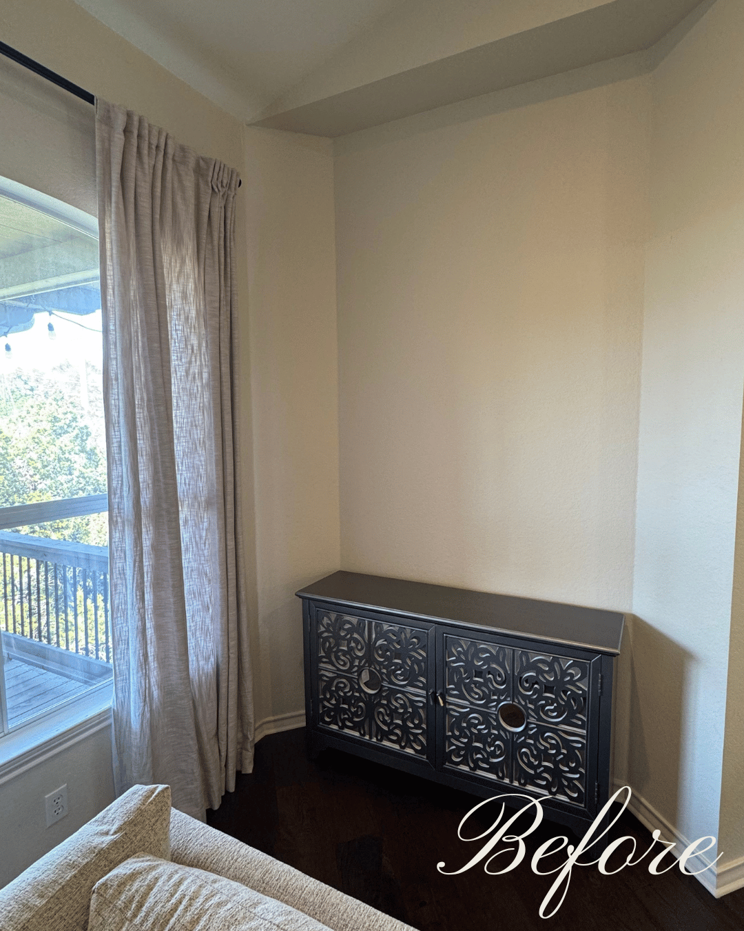 A "before" image of an awkward and empty wall in a living room with a small cabinet and vastly empty wall.