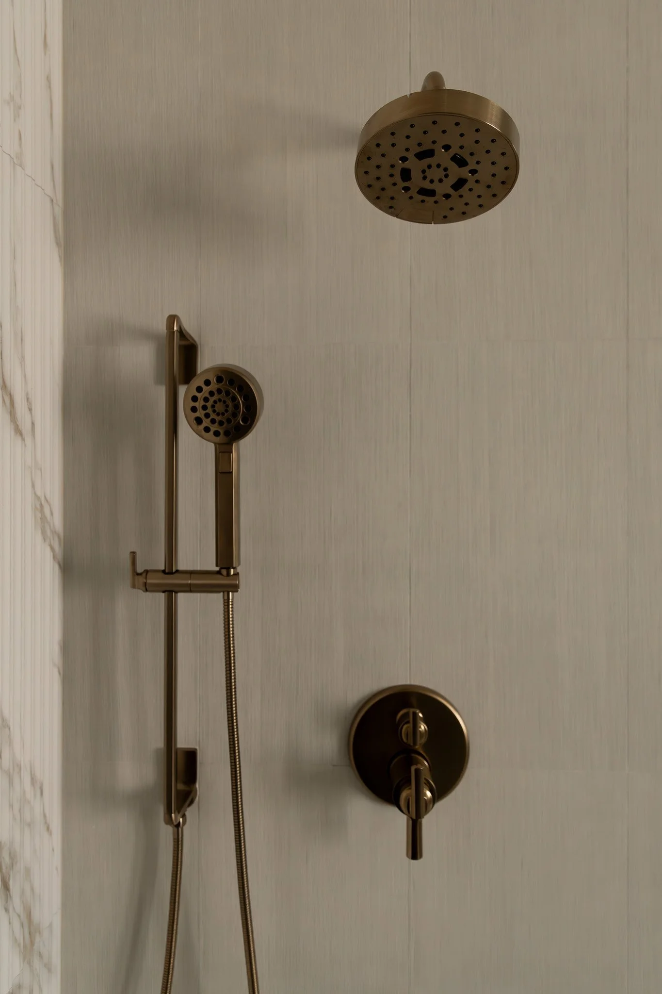 Elegant and sophisticated bathroom shower with reeded tile and brass plumbing fixtures.