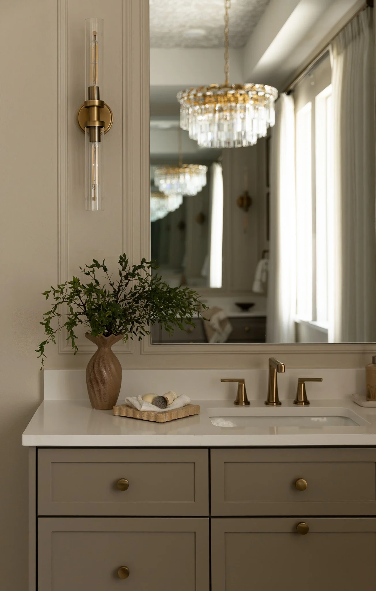 An elegant and sophisticated bathroom design with taupe cabinetry, romantic details and serene luxury feel.