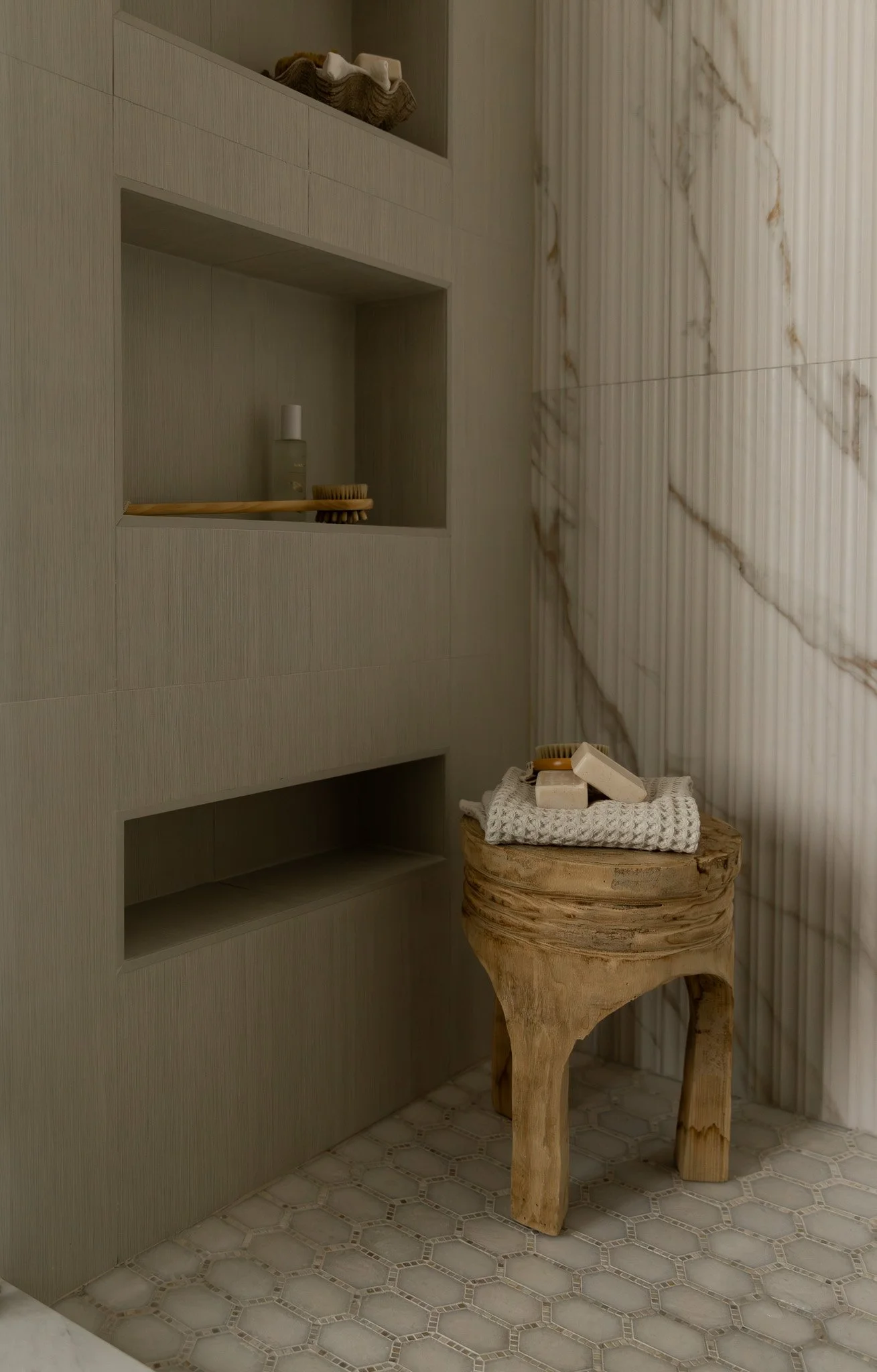 Elegant and sophisticated bathroom shower with reeded tile, multiple niches, marble shower pan tile.
