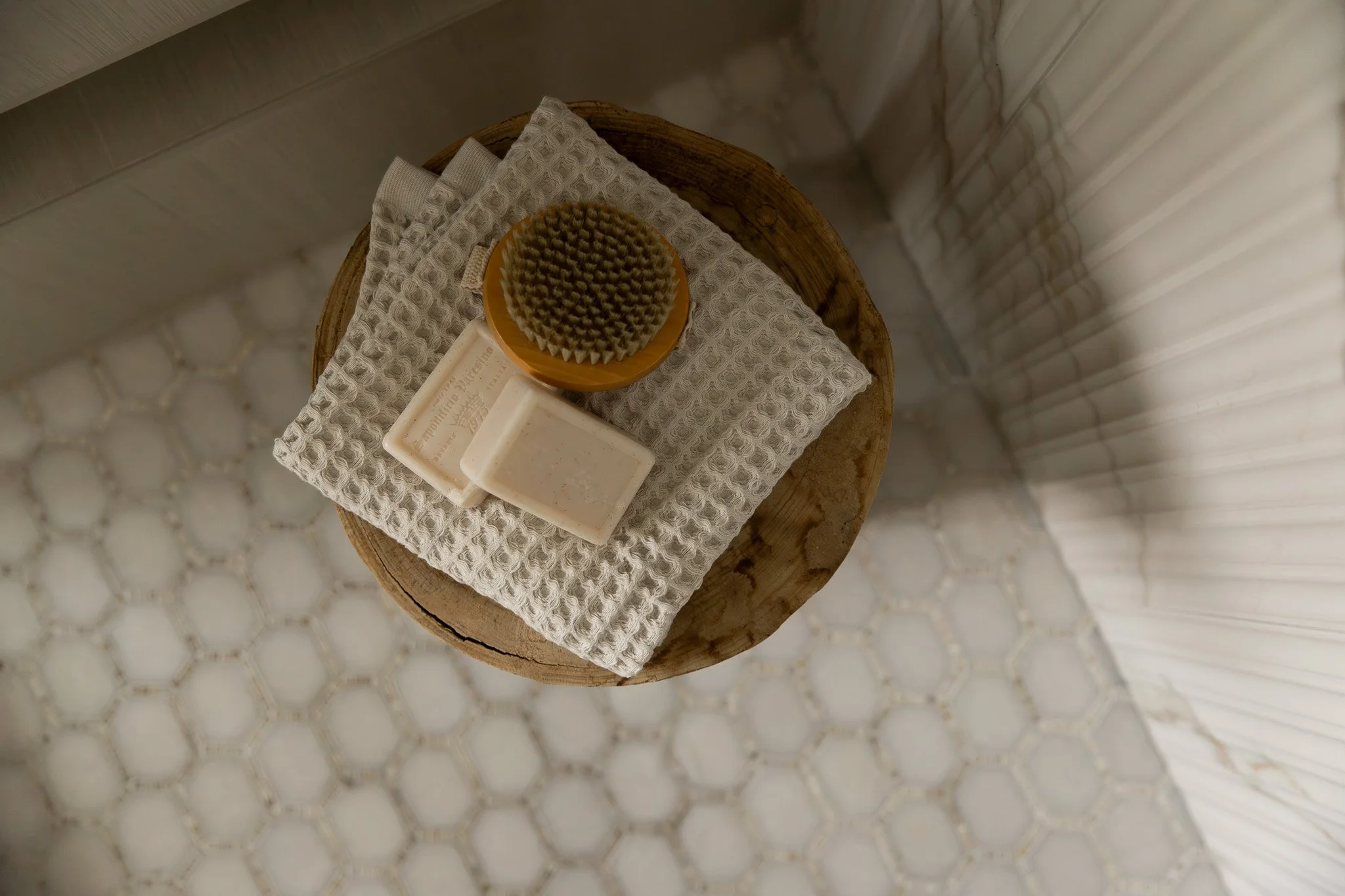 Close up shot of elegant and sophisticated bathroom shower with reeded tile, marble shower pan tile and spa-like accessories and decor.