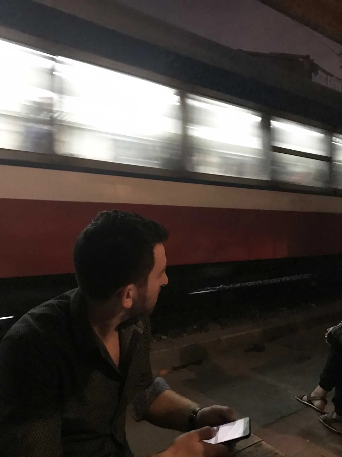 Danny drinking rice wine at a restaurant a few feet from a passing train.
