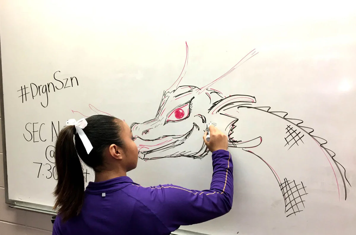 LSU gymnast Erin Macadaeg draws a fire breathing dragon on a whiteboard in the team locker room earlier this season.