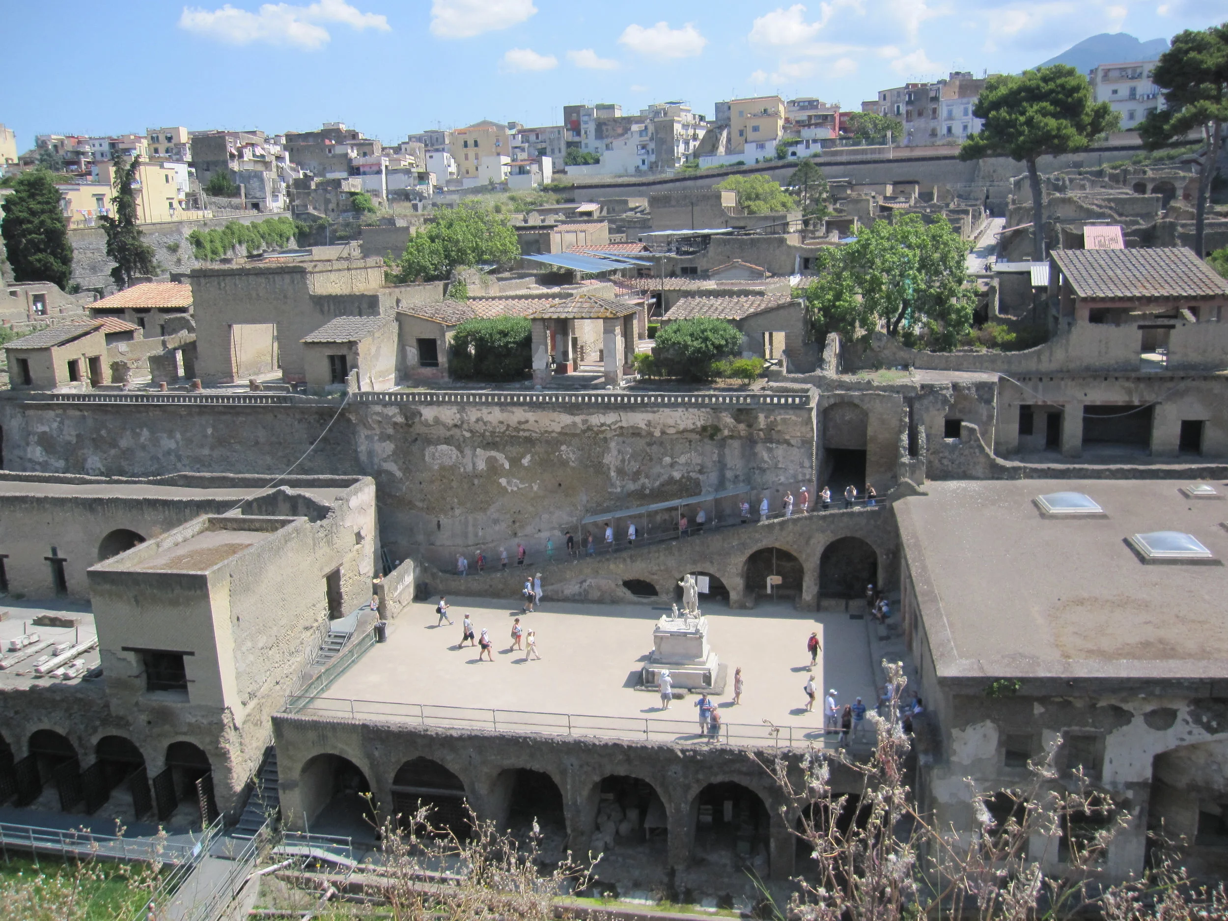 Visitors walking down the ramp to the terraced area, with the statue of the Roman emperor Baldo