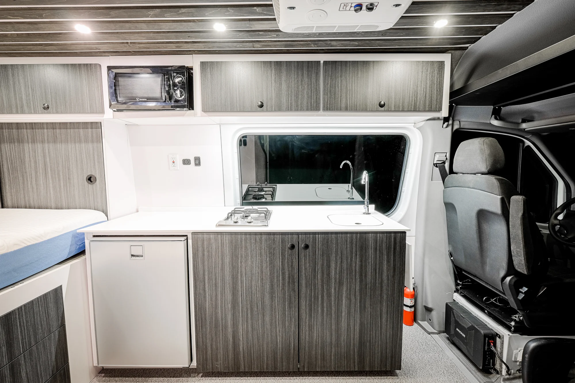 The Coleman Mach 8 A/C unit can be run off of the lithium batteries for short bursts, but can also be run off of shore power. The Kicker subwoofer gives an extra kick while cruising, and the high-mounted microwave comes in handy for quick meals on the road. 